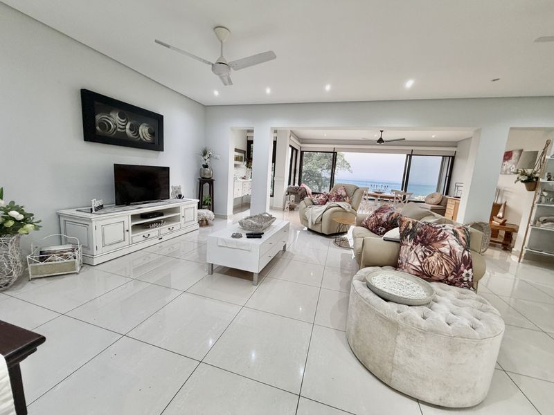 Spacious open-plan living area featuring large format floor tiles, recessed lighting, ceiling fans, and expansive sliding doors leading to an outdoor view.