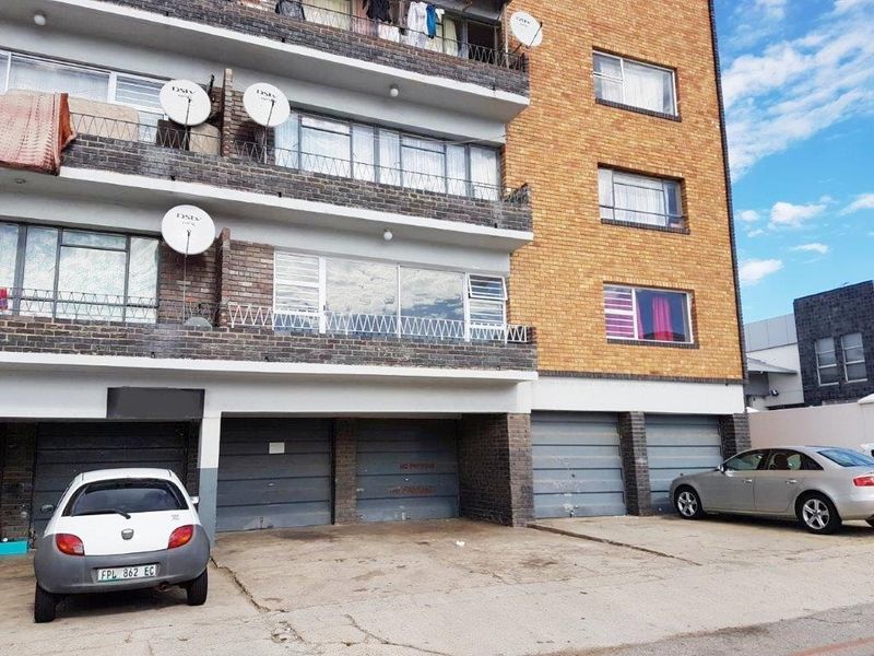 Front elevation of a multi-story apartment building featuring brick facade, private balconies, and ground-level garage access.