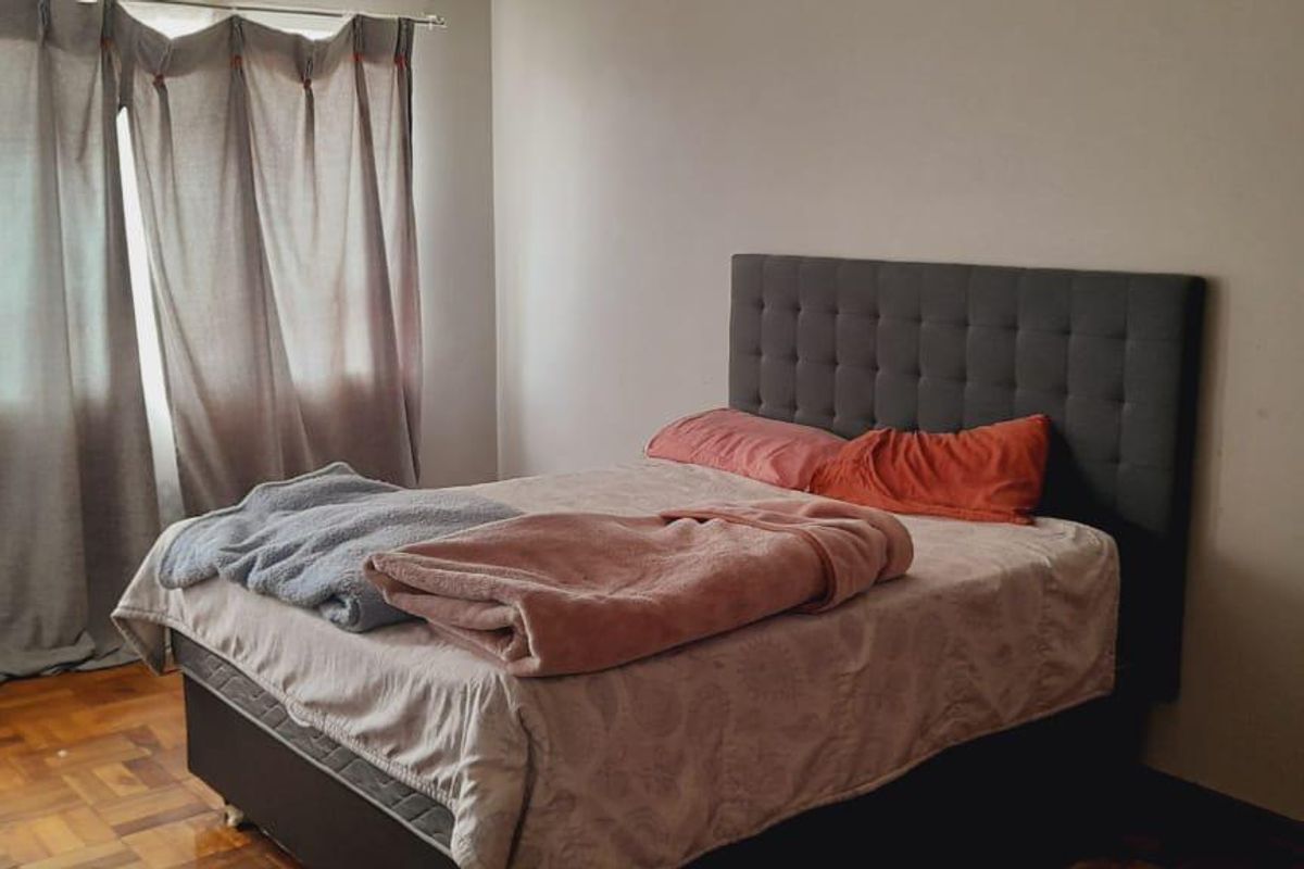 A bedroom featuring classic parquet flooring and neutral wall finishes, providing a functional space ready for personalization.