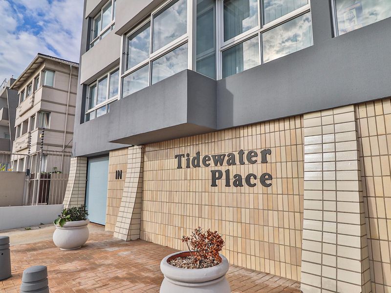 Front entrance facade of Tidewater Place apartment building featuring tiled exterior walls, aluminium window frames, and paved access area.
