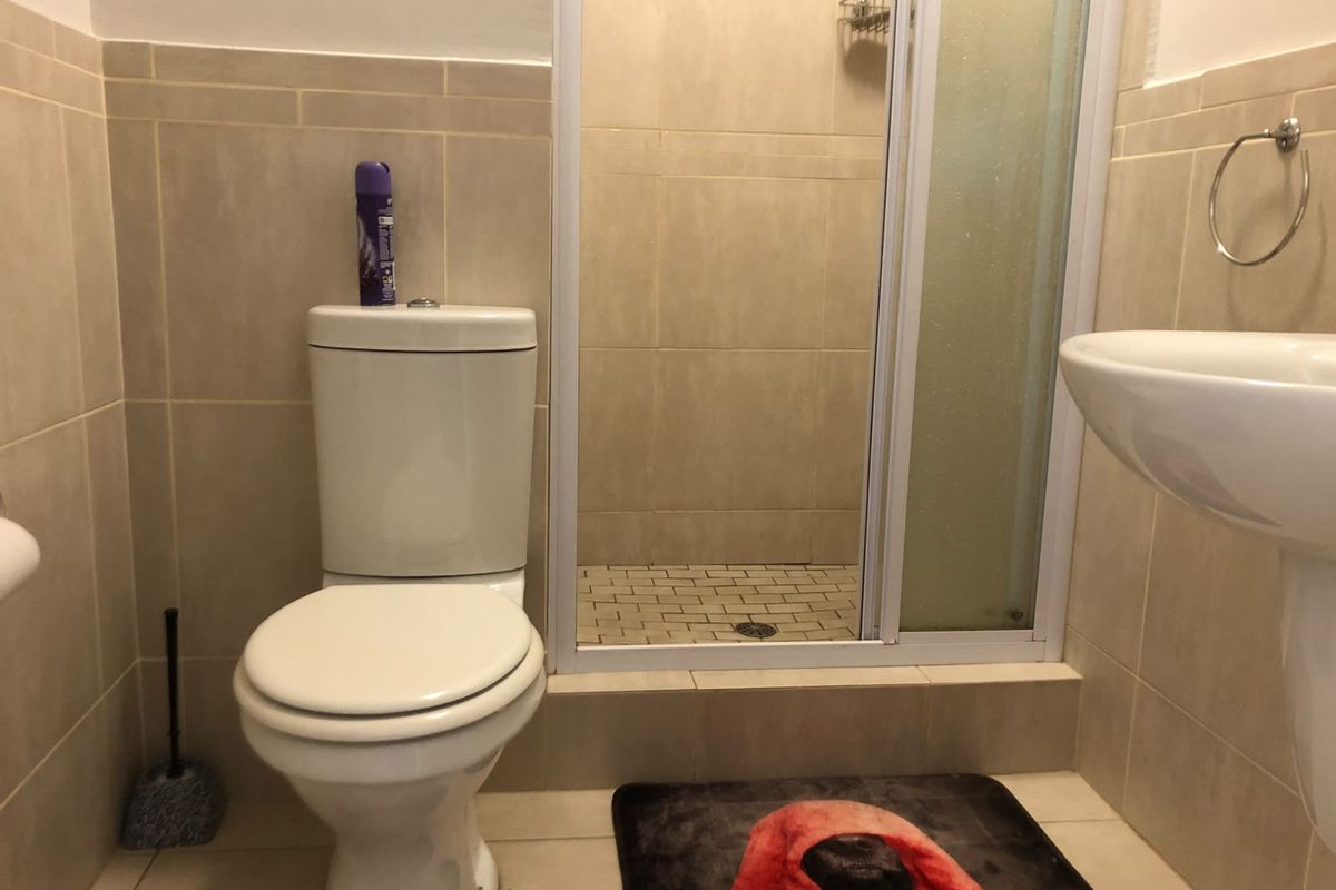 A functional bathroom featuring a pedestal basin, a toilet, and a tiled shower enclosure with a glass door.