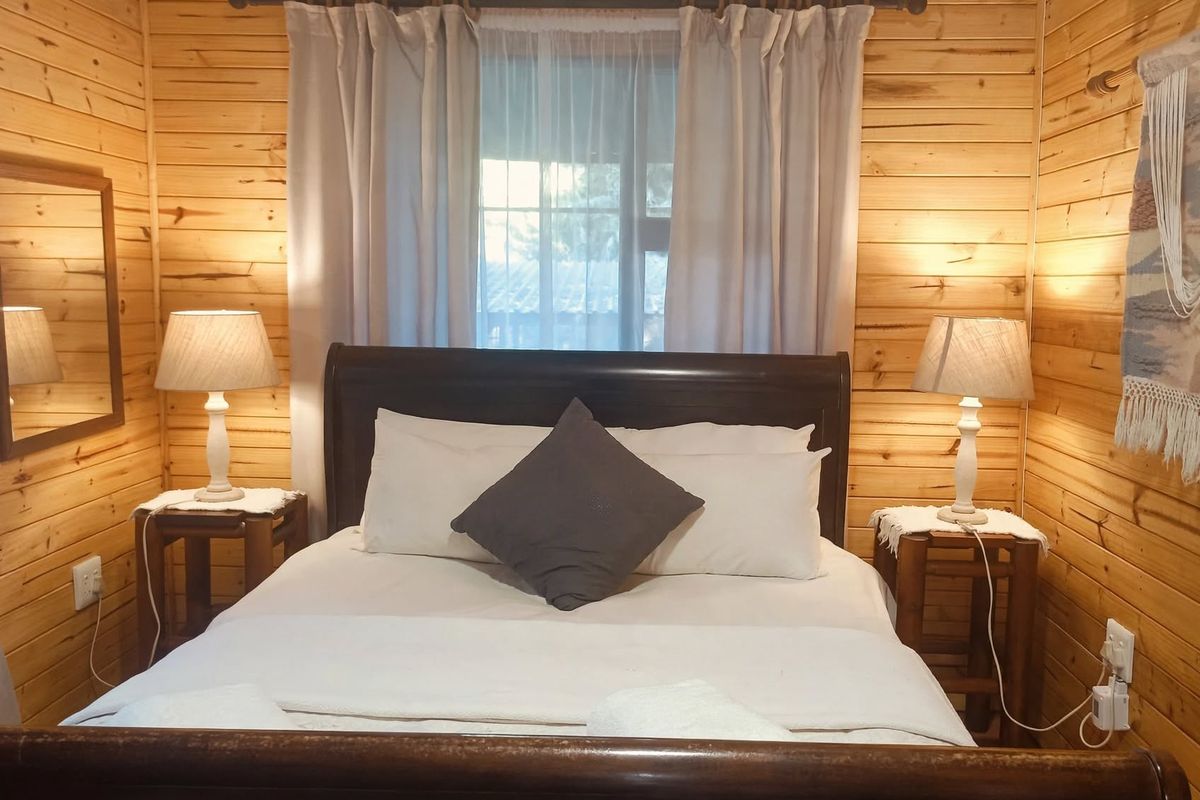 A cozy bedroom featuring warm timber wall cladding and a window with natural light, creating a rustic and inviting atmosphere.