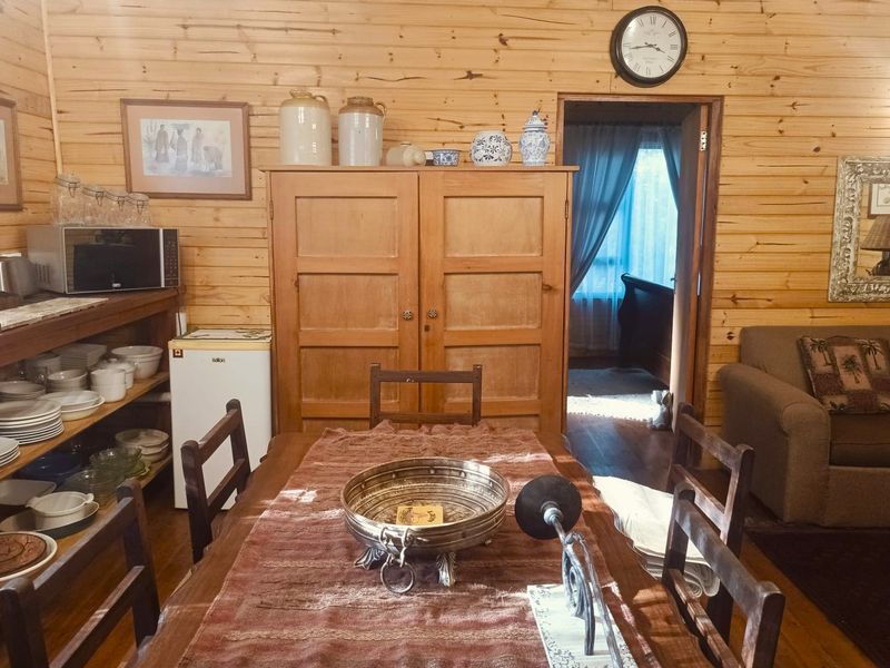A rustic dining area featuring natural timber wall cladding and wooden flooring, creating a warm and traditional cottage atmosphere.