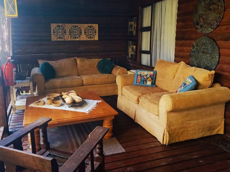 A covered outdoor patio area featuring rustic timber log walls and wooden decking, providing a cozy space for relaxation.