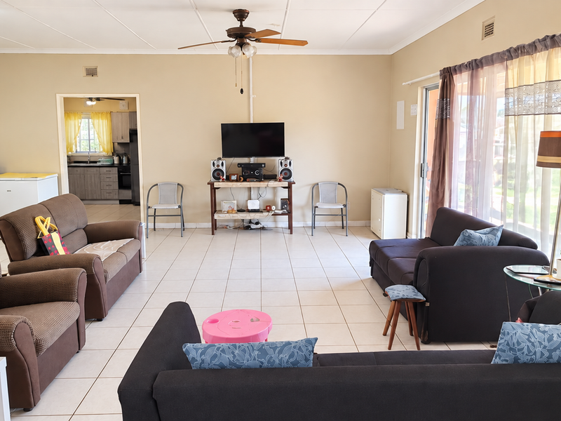 Spacious open-plan living area featuring tiled flooring, a ceiling fan, and direct access to the outdoors through a sliding glass door.