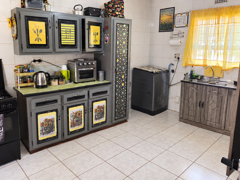A functional kitchen featuring tiled walls and flooring, built-in cabinetry, a gas stove with oven, and a double sink setup.