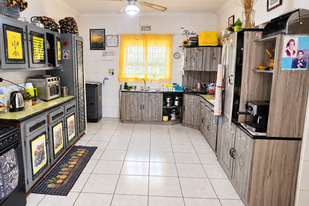 A functional kitchen featuring tiled walls and flooring, ample built-in cabinetry, a gas stove, and a double sink with a window view.