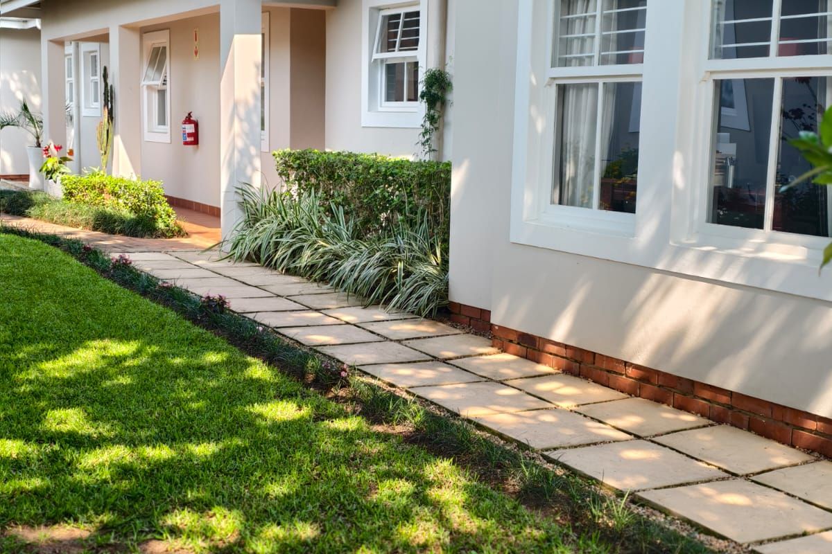 A well-maintained rear exterior view of the townhouse featuring a paved walkway, landscaped garden, and classic sash windows.