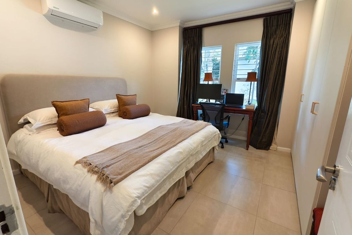 A well-maintained bedroom featuring tiled flooring, built-in cupboards, and a wall-mounted split-system air conditioner.