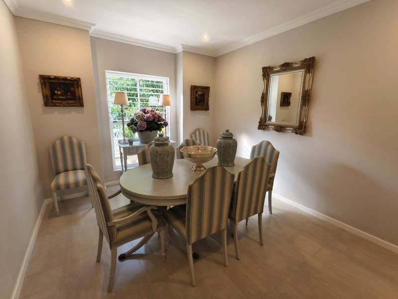 A well-maintained dining room featuring neutral tiled flooring, crown molding, recessed lighting, and window shutters, providing a bright and elegant space for meals.