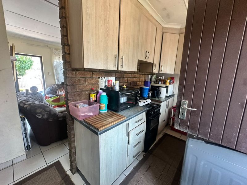 Compact kitchen featuring laminate cabinetry, exposed brick accents, and a freestanding stove, with direct access to the adjacent living area.
