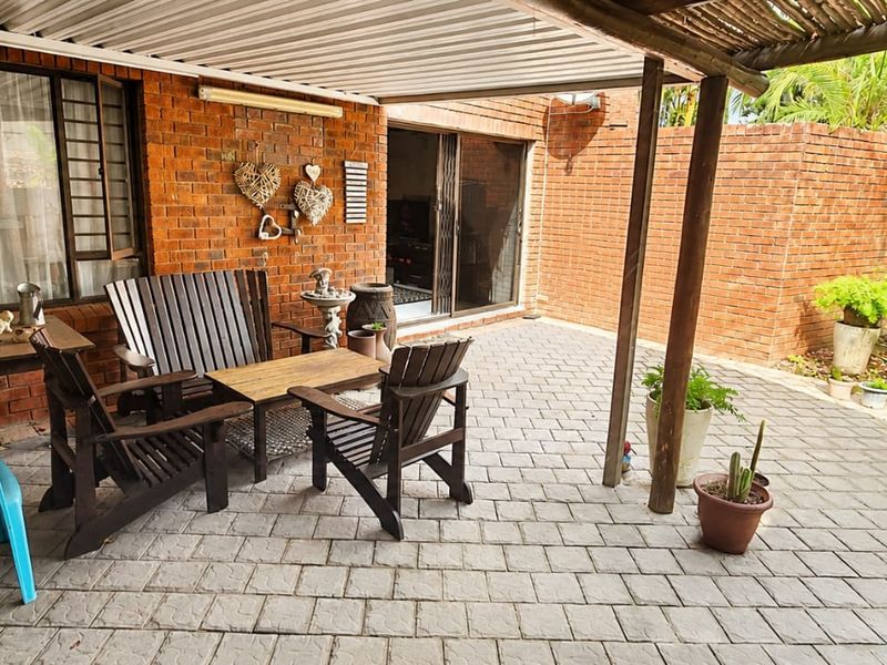 A covered outdoor patio area featuring brick walls, paved flooring, and direct access to the interior through sliding glass doors.