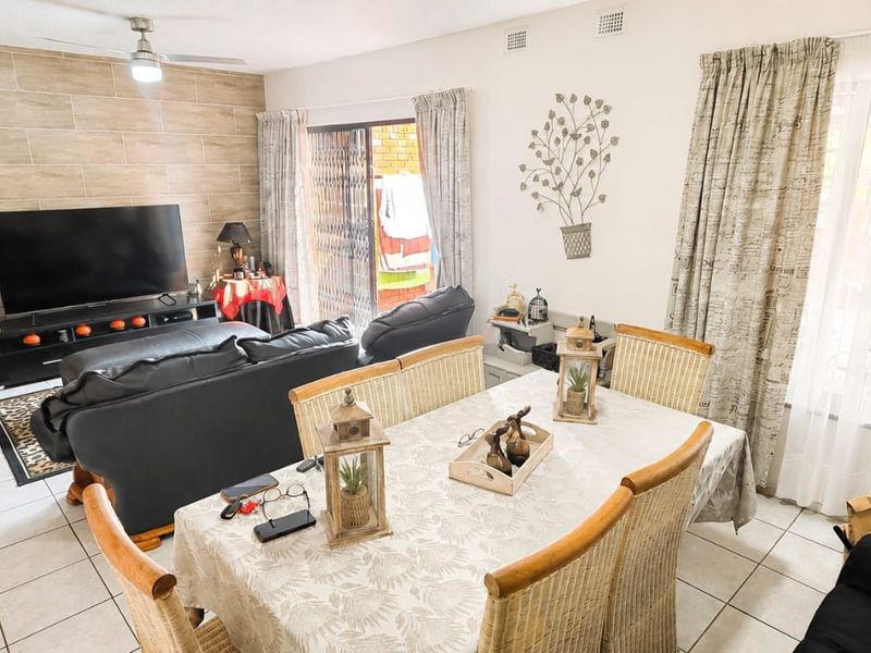 Open plan living and dining area featuring tiled flooring, a wood-look feature wall, and sliding door access to the exterior.