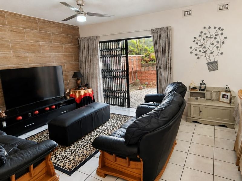 Open-plan living and dining area featuring tiled floors, a feature wall, and sliding door access to the rear patio.