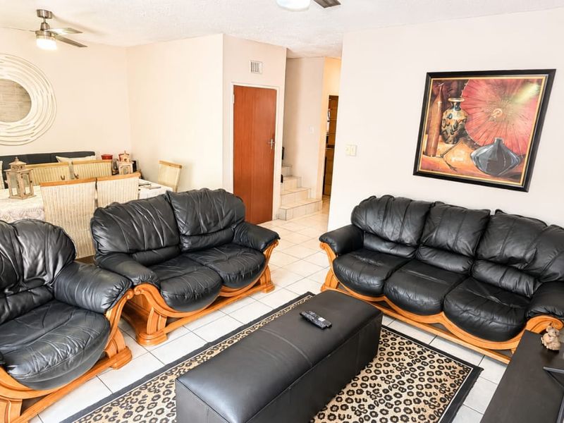 Open plan living and dining area featuring tiled flooring and a ceiling fan, with a staircase leading to the upper level.