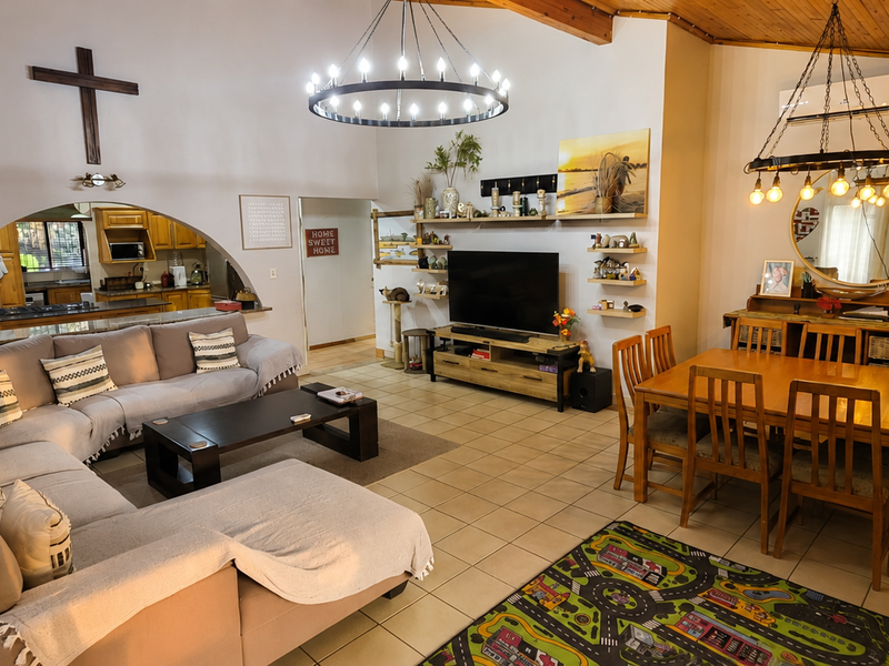 Spacious open-plan living and dining area featuring a vaulted timber ceiling, tiled flooring, and a distinctive archway leading to the kitchen.
