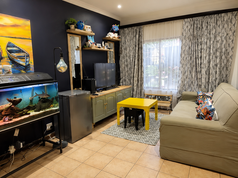A cozy living room featuring tiled flooring, recessed lighting, and built-in cabinetry, offering a functional space with a unique glass block architectural detail.