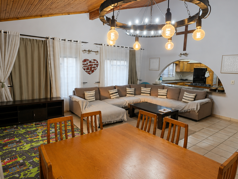 Spacious open-plan living and dining area featuring a vaulted timber ceiling, tiled floors, and an arched opening leading to a functional kitchen.