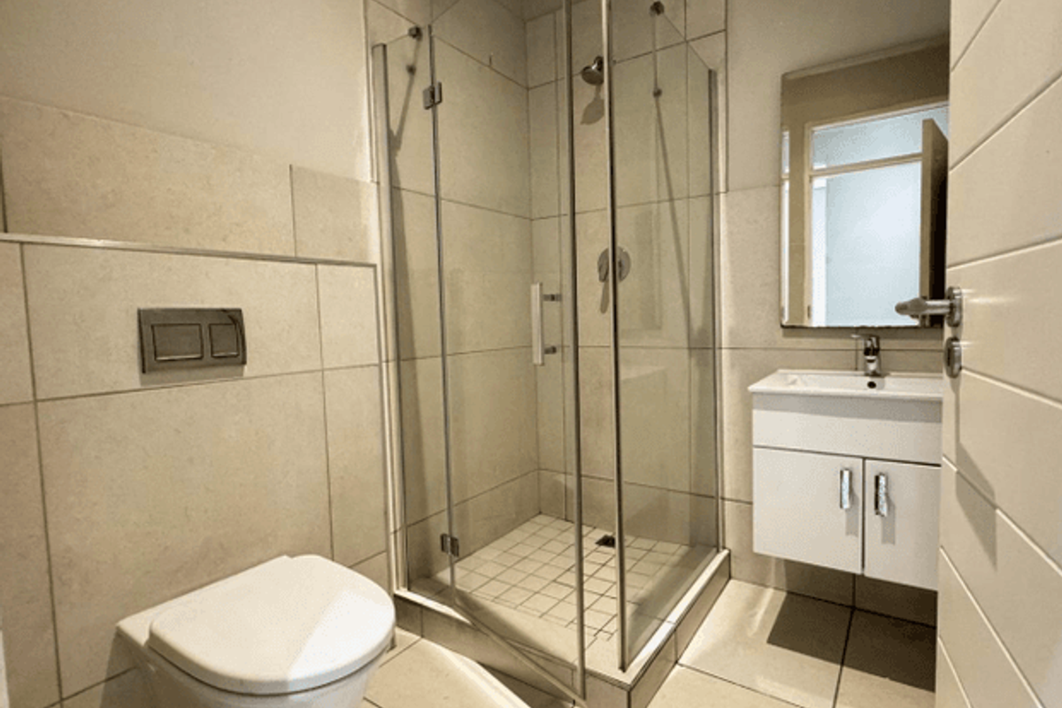 Modern bathroom featuring a wall-hung toilet, glass shower enclosure, and a sleek vanity cabinet with basin.