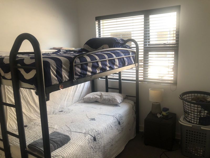 A functional bedroom featuring a window with fitted venetian blinds, providing natural light and privacy.