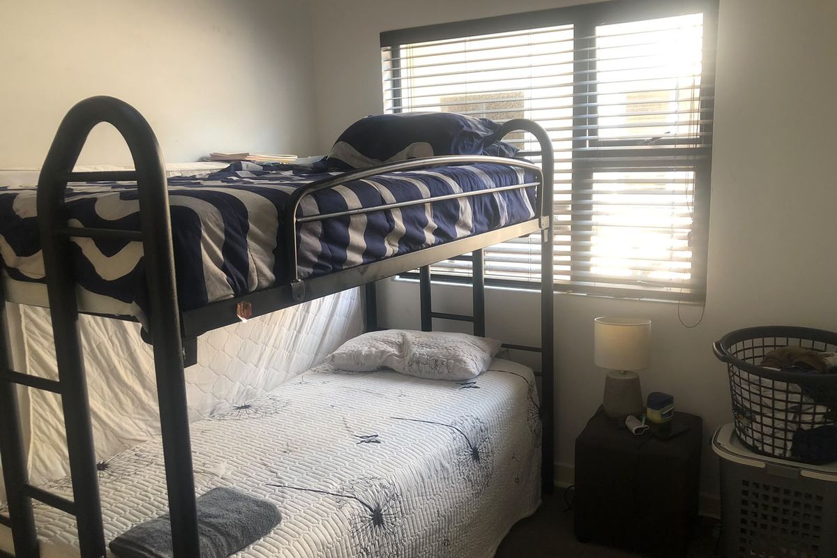 A functional bedroom featuring a window with fitted venetian blinds, providing natural light and privacy.