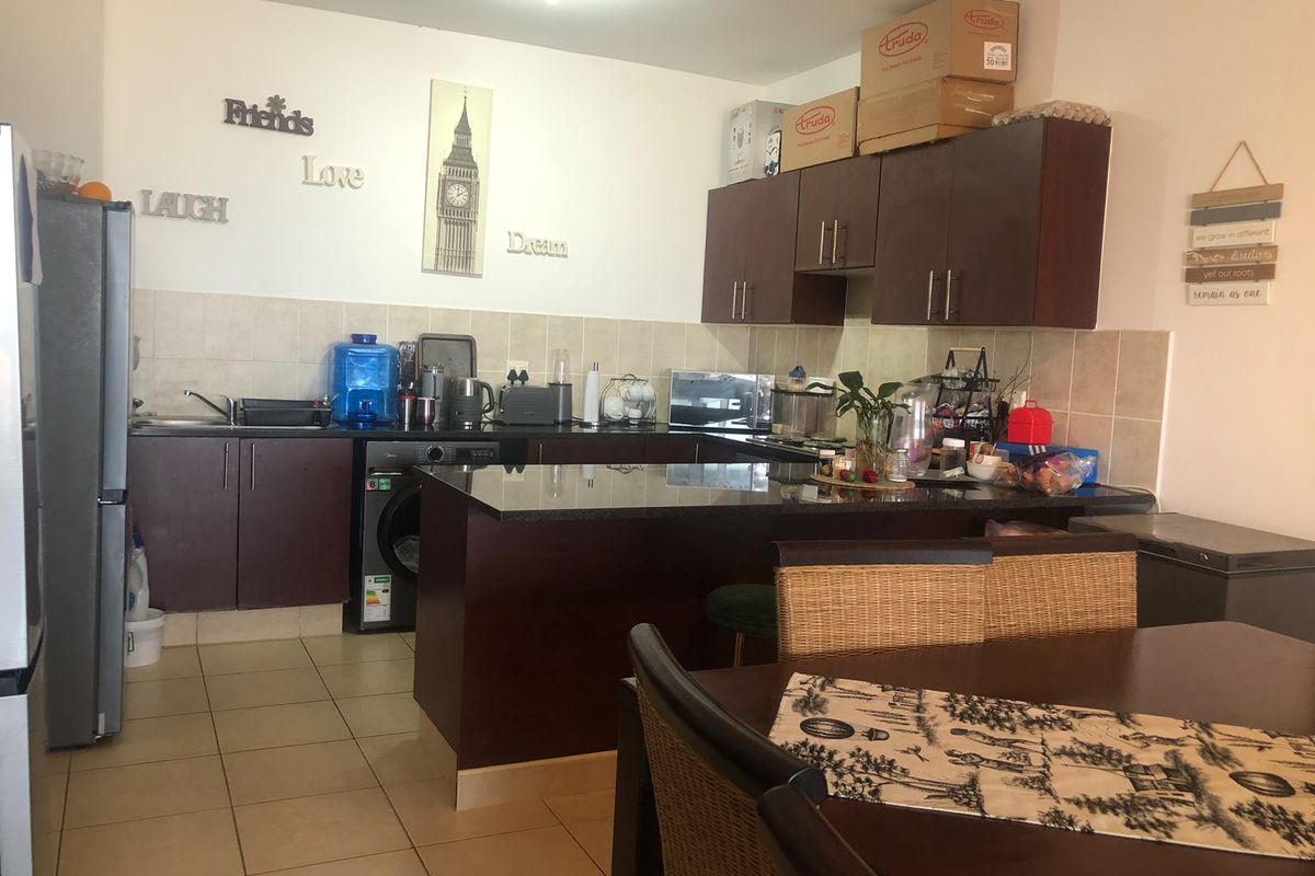 A functional kitchen featuring dark wood cabinetry, granite countertops, tiled backsplash, and an integrated washing machine, offering a practical layout for daily use.