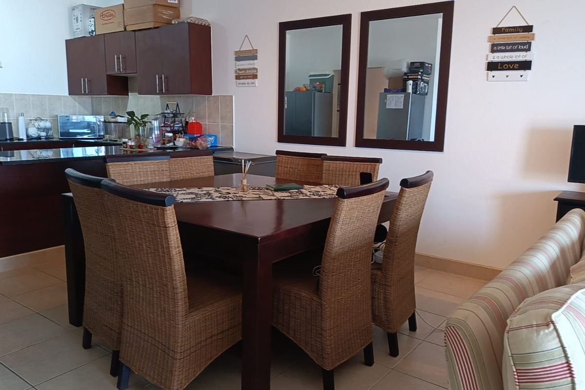 Open plan living and dining area featuring tiled floors and a functional kitchen with dark wood cabinetry and granite countertops.
