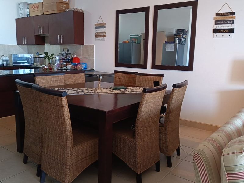 Open plan living and dining area featuring tiled floors and a functional kitchen with dark wood cabinetry and granite countertops.