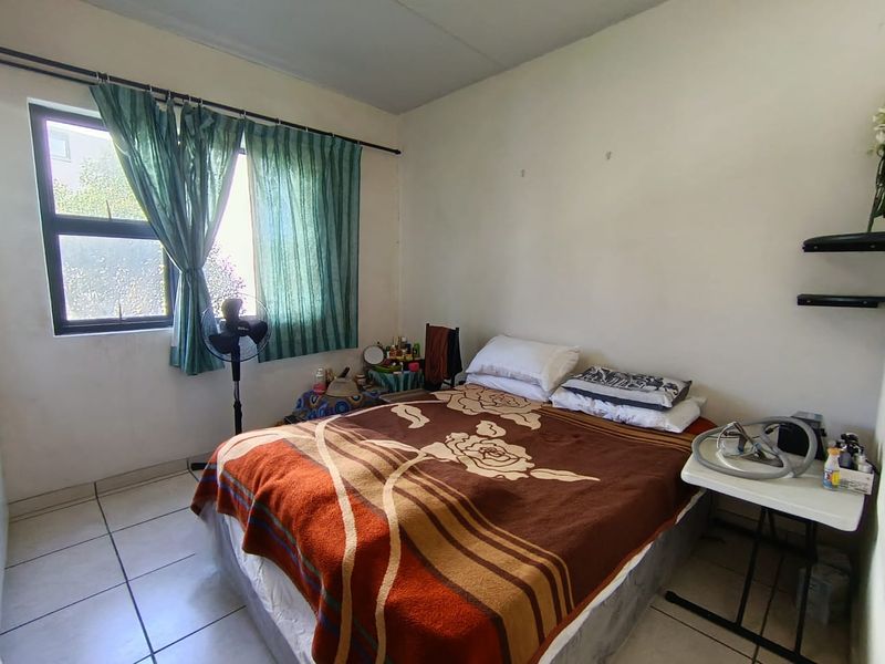 A functional bedroom featuring tiled flooring and an aluminium window frame, requiring minor cosmetic updates to improve its overall presentation.