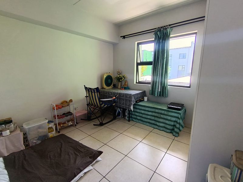 A bedroom featuring tiled flooring and a large casement window, offering a functional space ready for personalization and updated interior design.