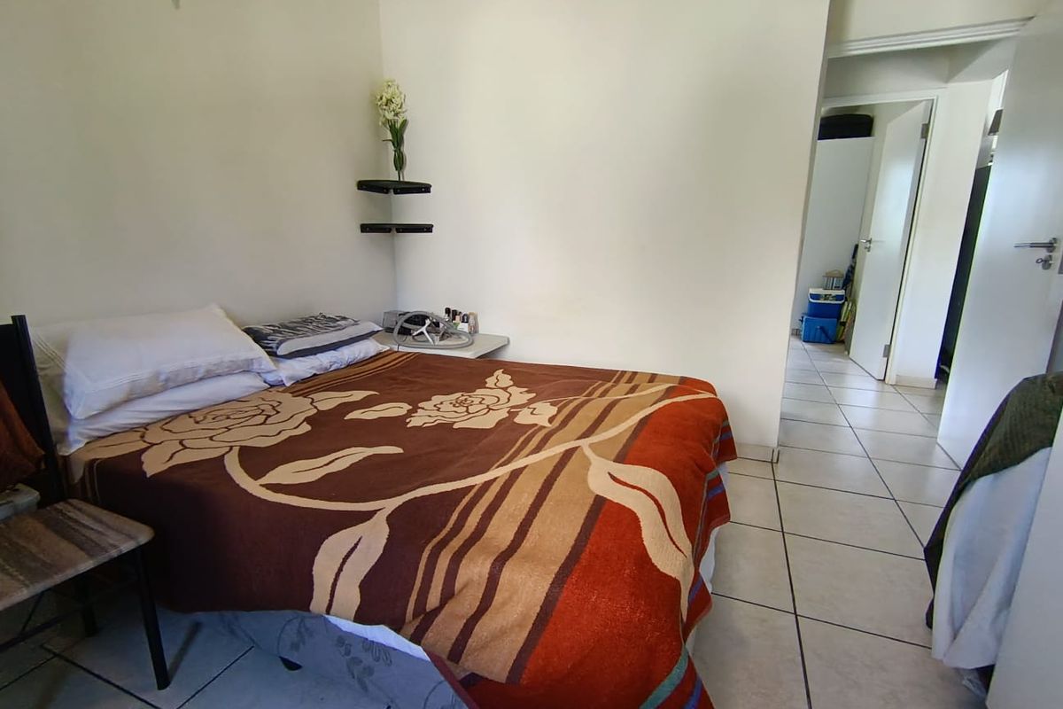 A bedroom featuring tiled flooring and neutral wall finishes, providing a functional space with direct access to the hallway.
