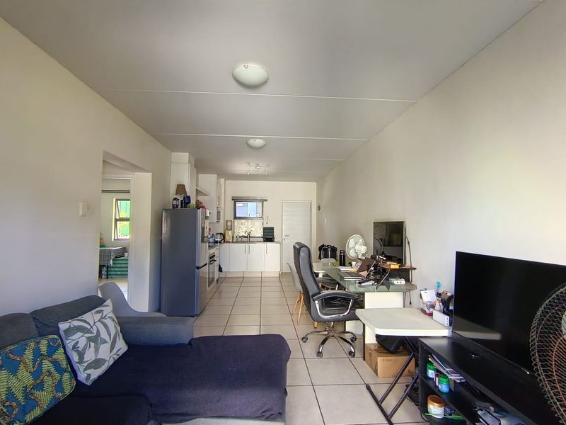 Open plan living area featuring tiled flooring and a functional kitchen with built-in cabinetry and appliances.