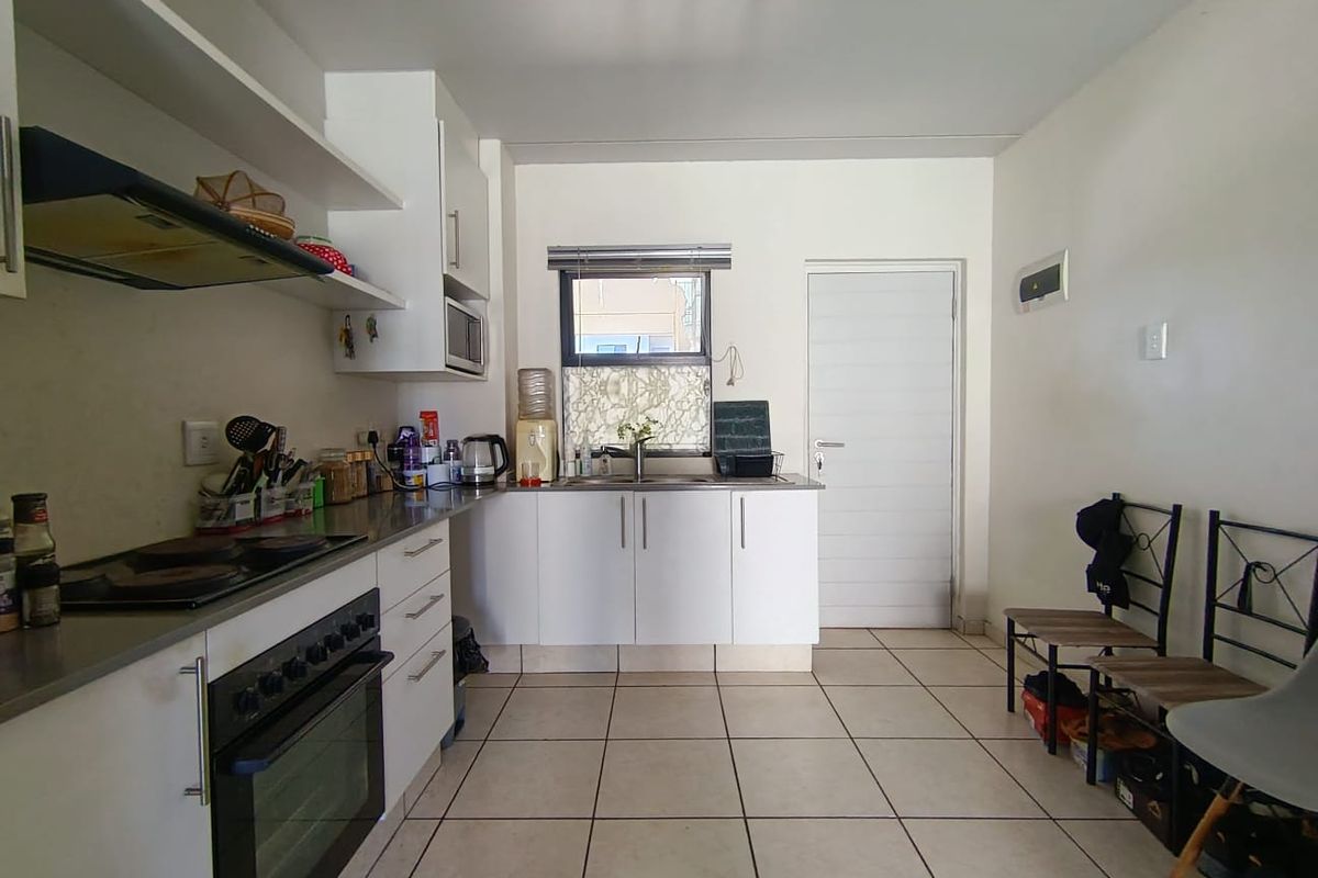 A functional kitchen featuring built-in cabinetry, an electric oven with hob, extractor fan, and tiled flooring, offering a practical layout for daily use.