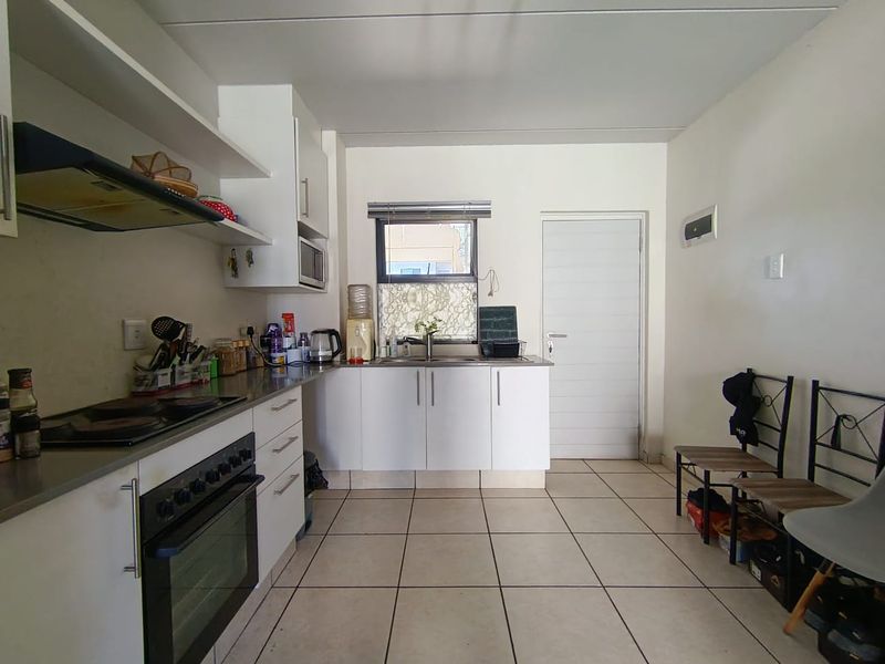 A functional kitchen featuring built-in cabinetry, an electric oven with hob, extractor fan, and tiled flooring, offering a practical layout for daily use.