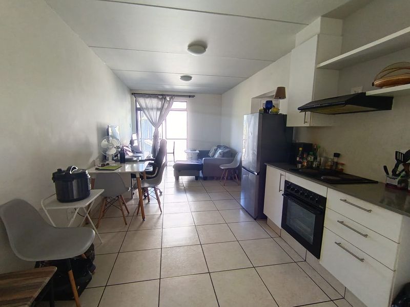 Open-plan living area featuring a functional kitchen with built-in oven and hob, tiled flooring, and direct access to an outdoor space.