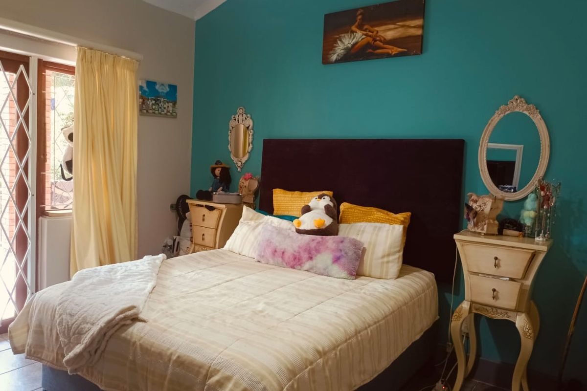 A bedroom featuring tiled flooring, a vaulted ceiling, and a sliding door with a security gate providing access to the exterior.