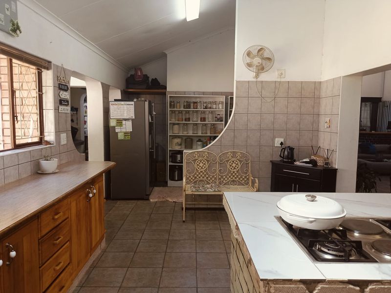 A functional kitchen featuring wooden cabinetry, tiled backsplash, and a central island with a built-in hob, offering a practical layout for daily cooking.