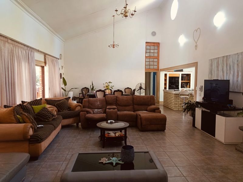 Spacious open-plan living area featuring vaulted ceilings, tiled flooring, and a brick breakfast bar connecting to the kitchen space.