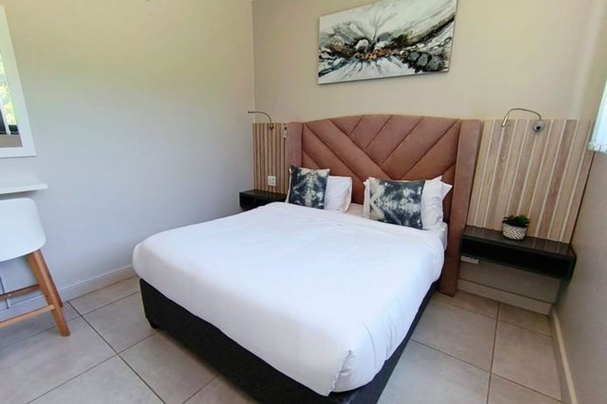 A well-maintained bedroom featuring tiled flooring, a custom built-in headboard with integrated bedside shelving, and wall-mounted reading lights.