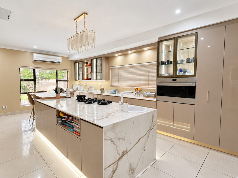 Modern kitchen featuring a marble-look island with gas cooktop, integrated cabinetry, built-in oven, and high-end finishes throughout.