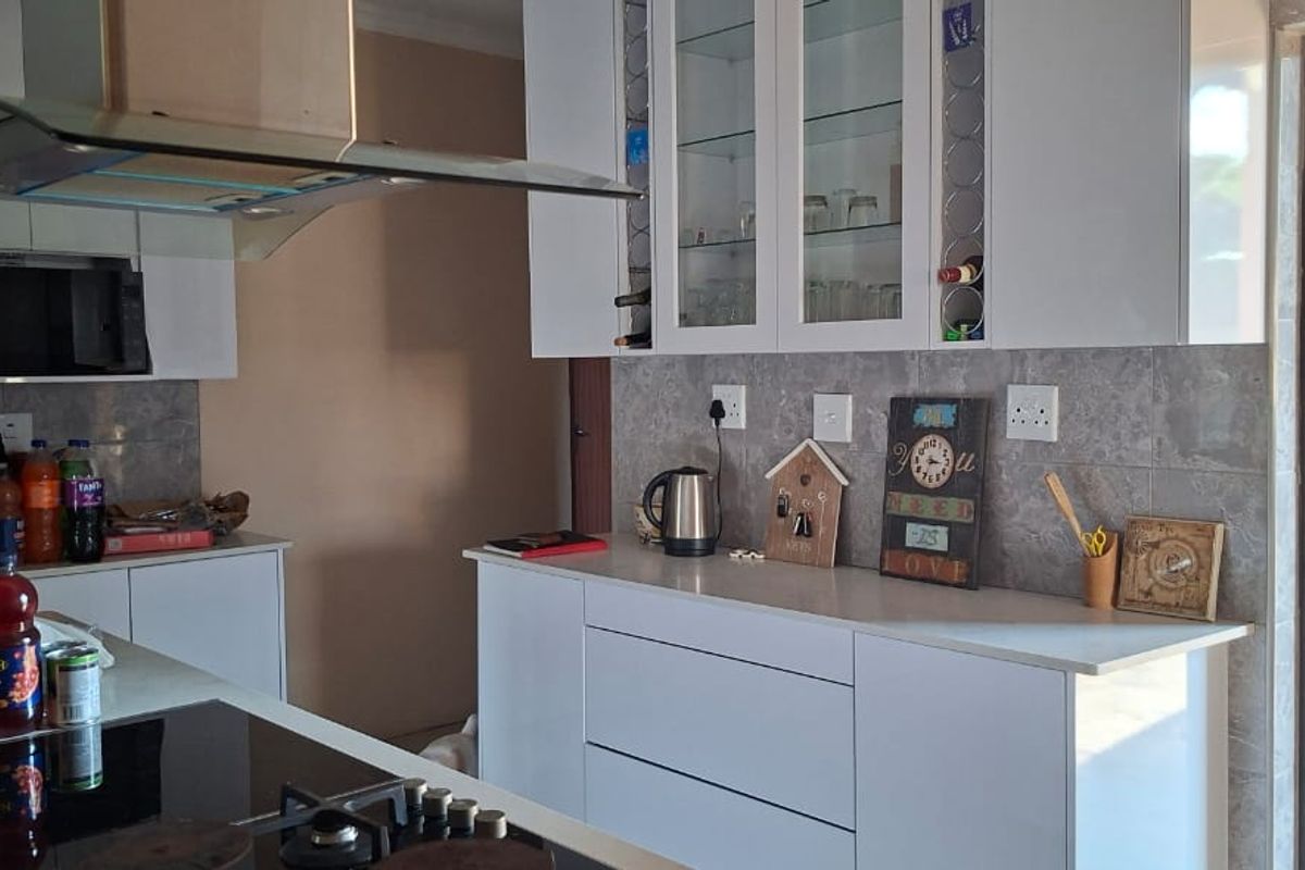 Modern kitchen featuring white cabinetry, stone countertops, tiled backsplash, built-in oven, hob, and a stainless steel extractor fan with direct access to the exterior.