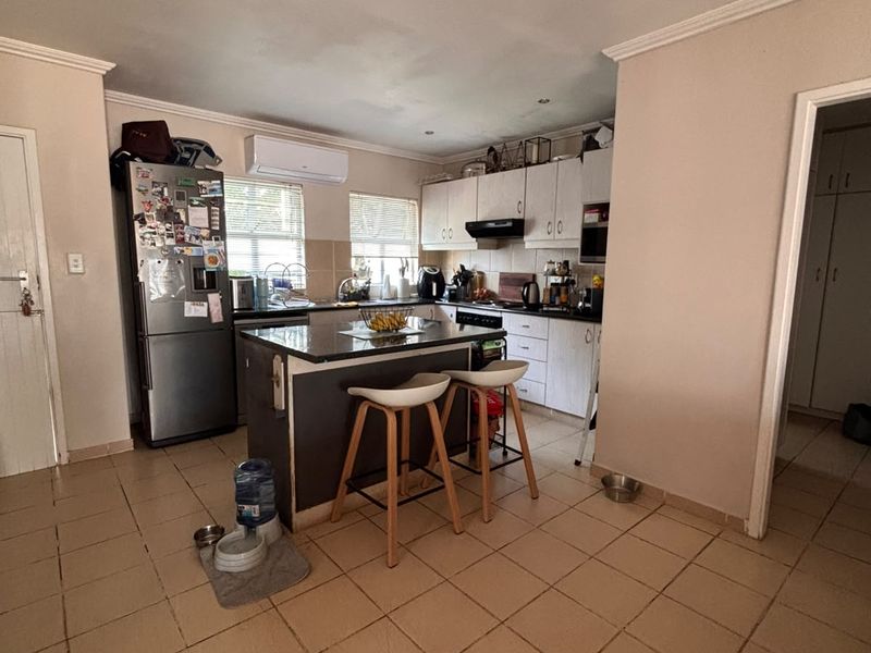 A functional kitchen featuring a central island, built-in cabinetry, and tiled flooring, equipped with an extractor fan and wall-mounted air conditioning unit.