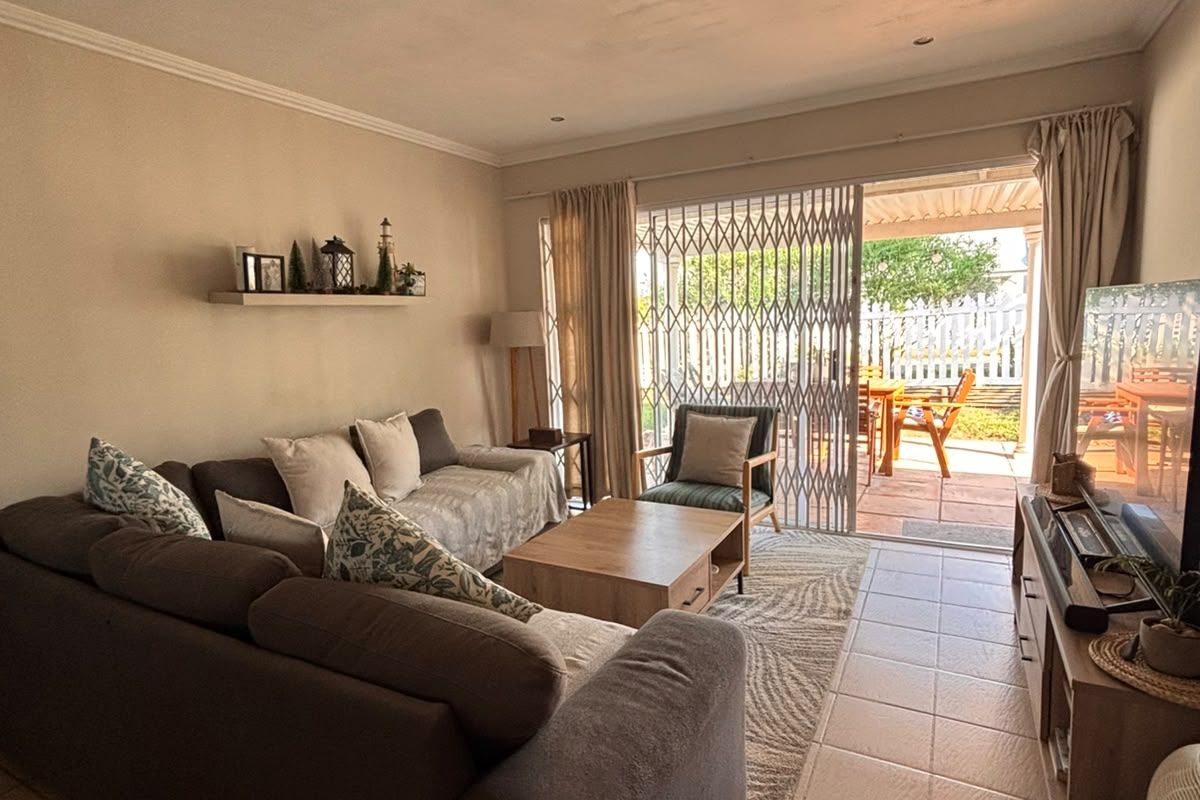 A comfortable living room featuring tiled floors, recessed lighting, and a sliding door providing direct access to an outdoor patio area.