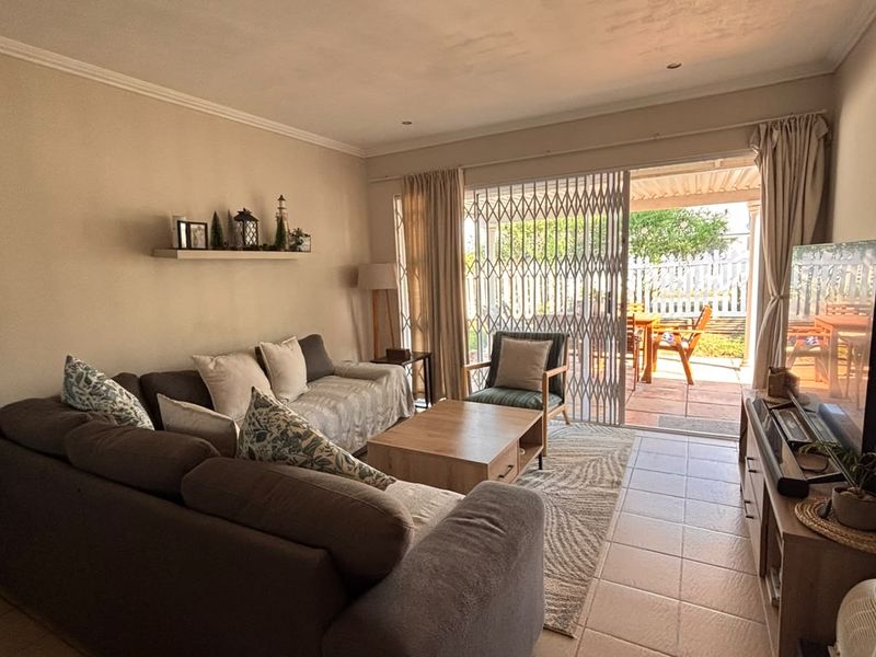 A comfortable living room featuring tiled floors, recessed lighting, and a sliding door providing direct access to an outdoor patio area.