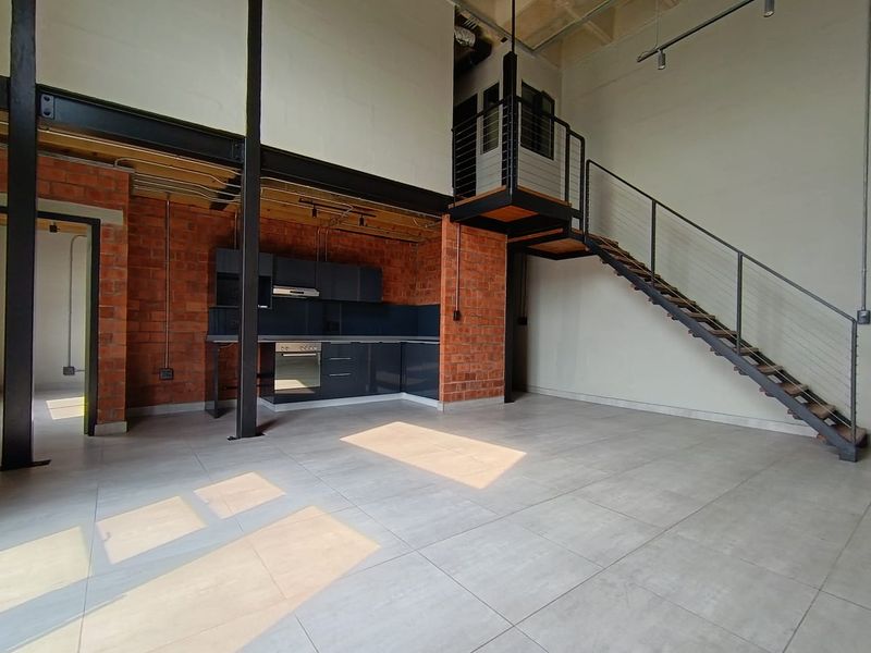 Modern open-plan apartment featuring industrial-style exposed brick walls, a sleek steel staircase, and a contemporary kitchen with integrated appliances.