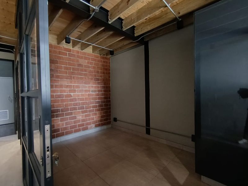 An industrial-style office space featuring exposed brickwork, timber ceiling joists, steel beams, and modern glass partitioning, offering a contemporary and versatile workspace.