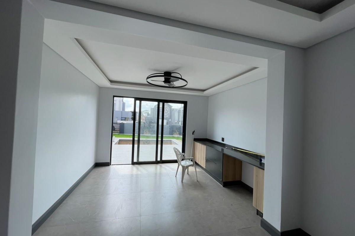 A bright, modern living space featuring recessed ceiling lighting, built-in cabinetry with stone countertops, and large sliding glass doors leading to the outdoor area.