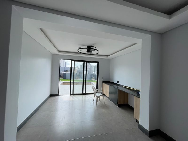 A bright, modern living space featuring recessed ceiling lighting, built-in cabinetry with stone countertops, and large sliding glass doors leading to the outdoor area.