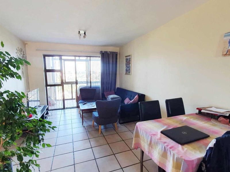 Open-plan living and dining area featuring tiled flooring and a sliding glass door providing access to the balcony.