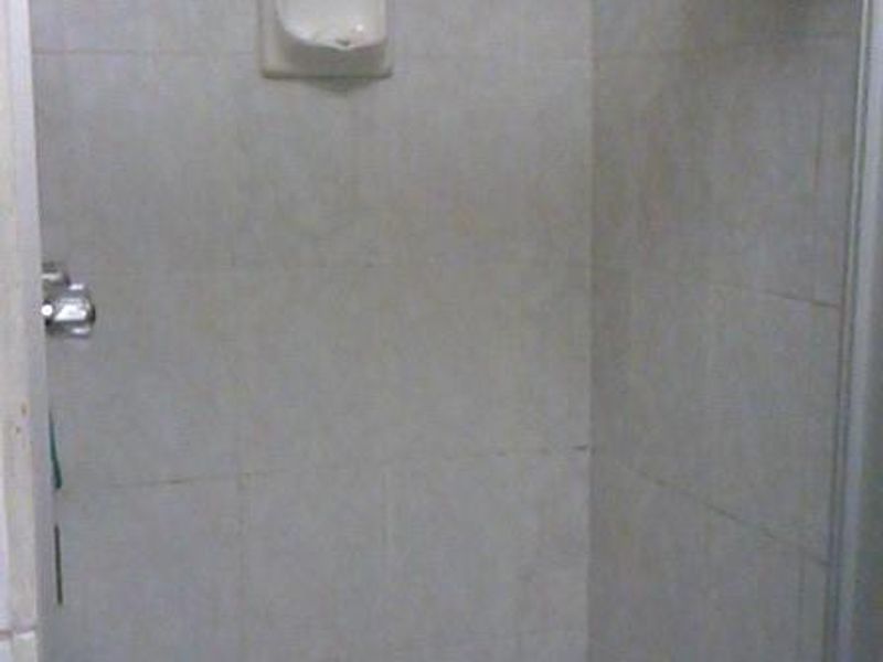 A basic shower enclosure featuring tiled walls and flooring with a built-in soap dish and standard shower fixtures.